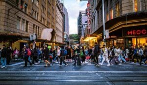 A bustling city street filled with pedestrians crossing during the twilight hours in an urban setting.